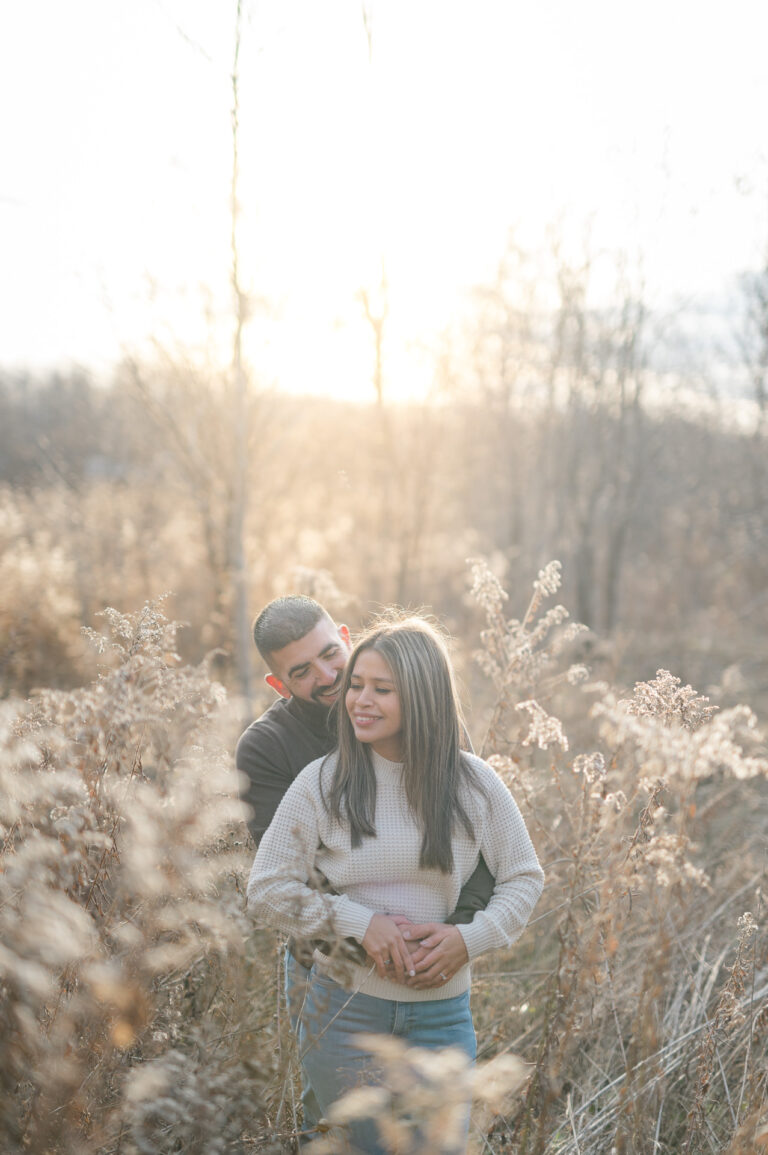 Sun setting on engaged couple in a field