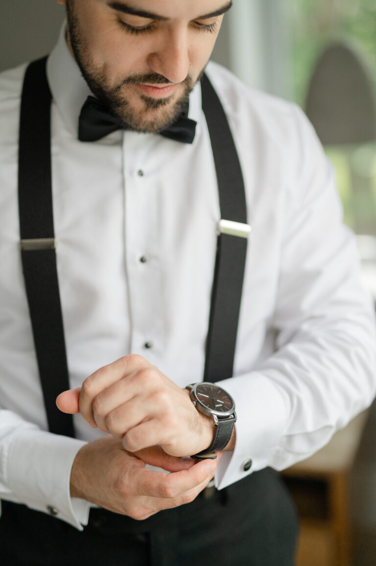 The groom puts his watch back in his toxedo