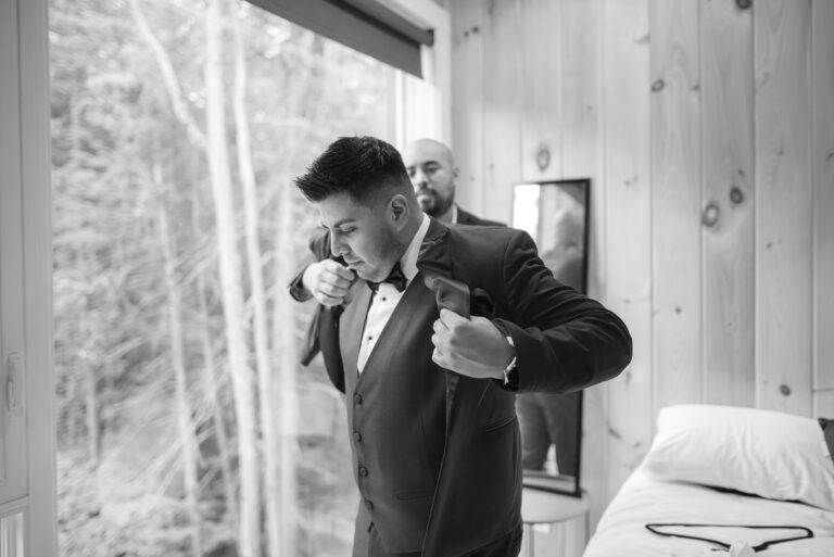 The groom finishes his preparation by putting on his black and white jacket.