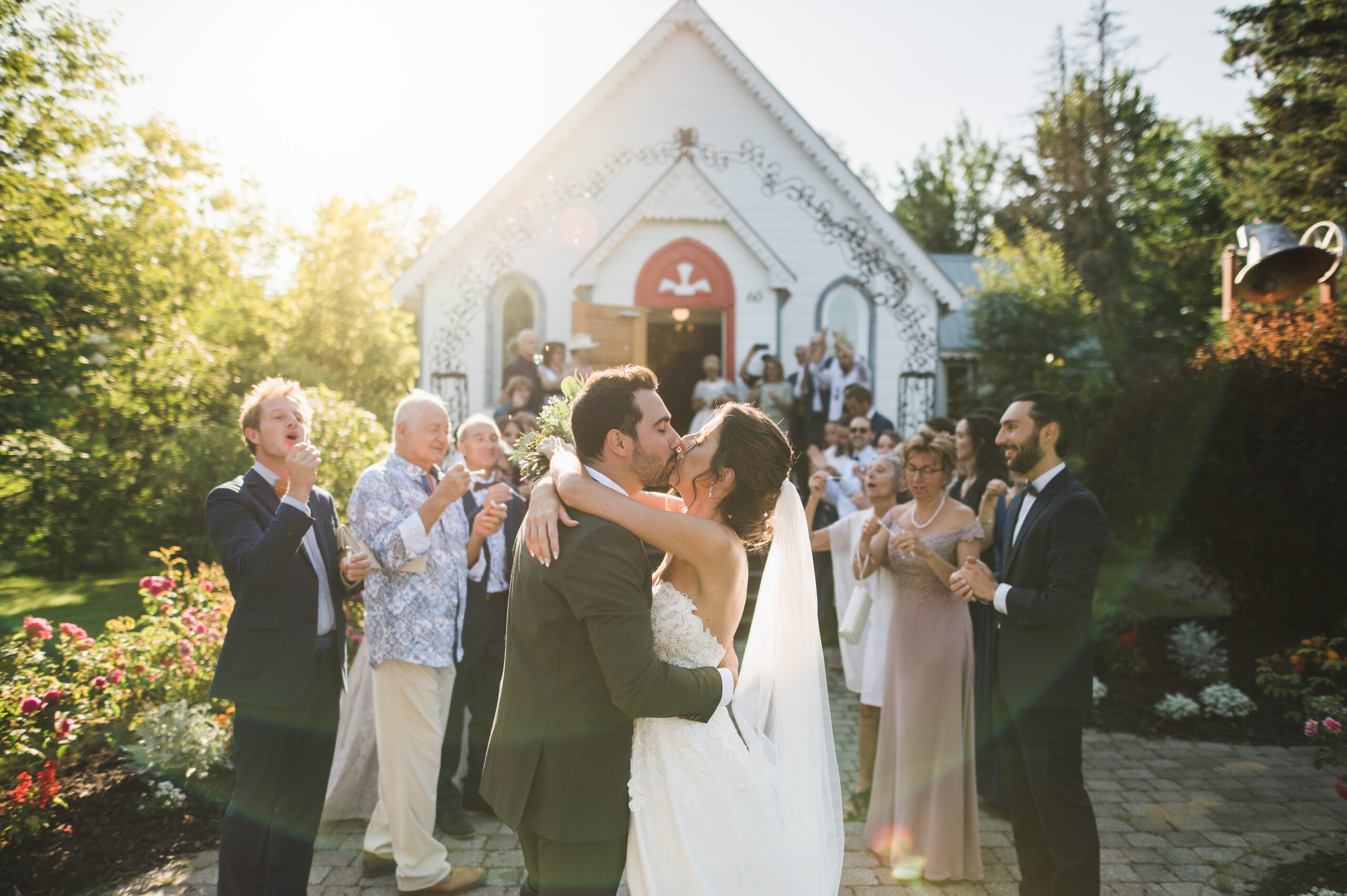 The bride and groom kiss in front of the chapel at Auberge Val Carroll