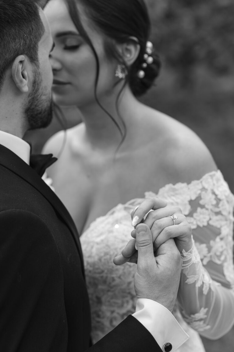 The bride and groom hold hands with the black and white wedding ring