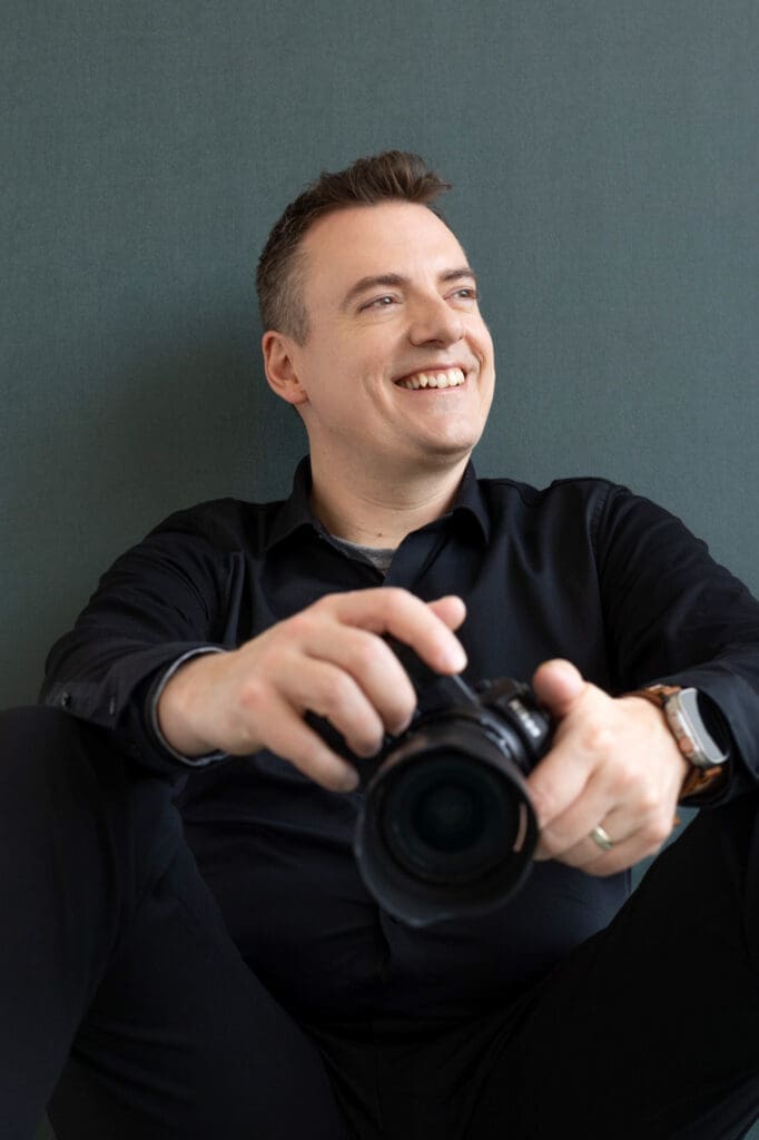 Olivier LG Photographe de mariage tout sourire avec son appareil photo dans les mains